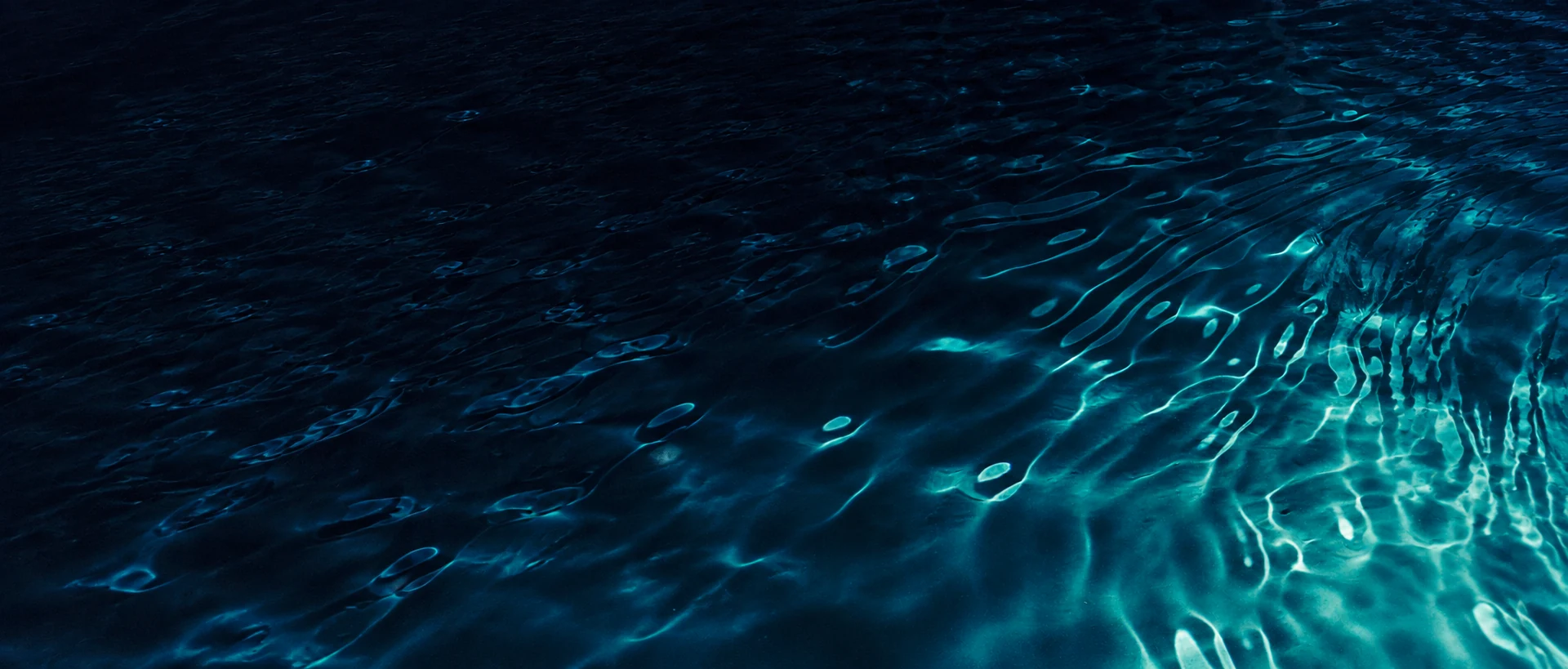 Cyan light reflected across ocean ripples